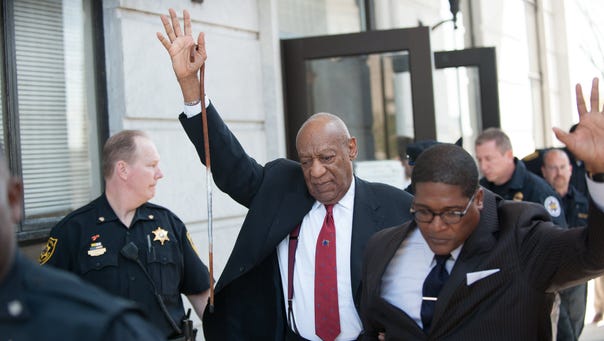 Bill Cosby raises gestures as he leaves the Montgomery