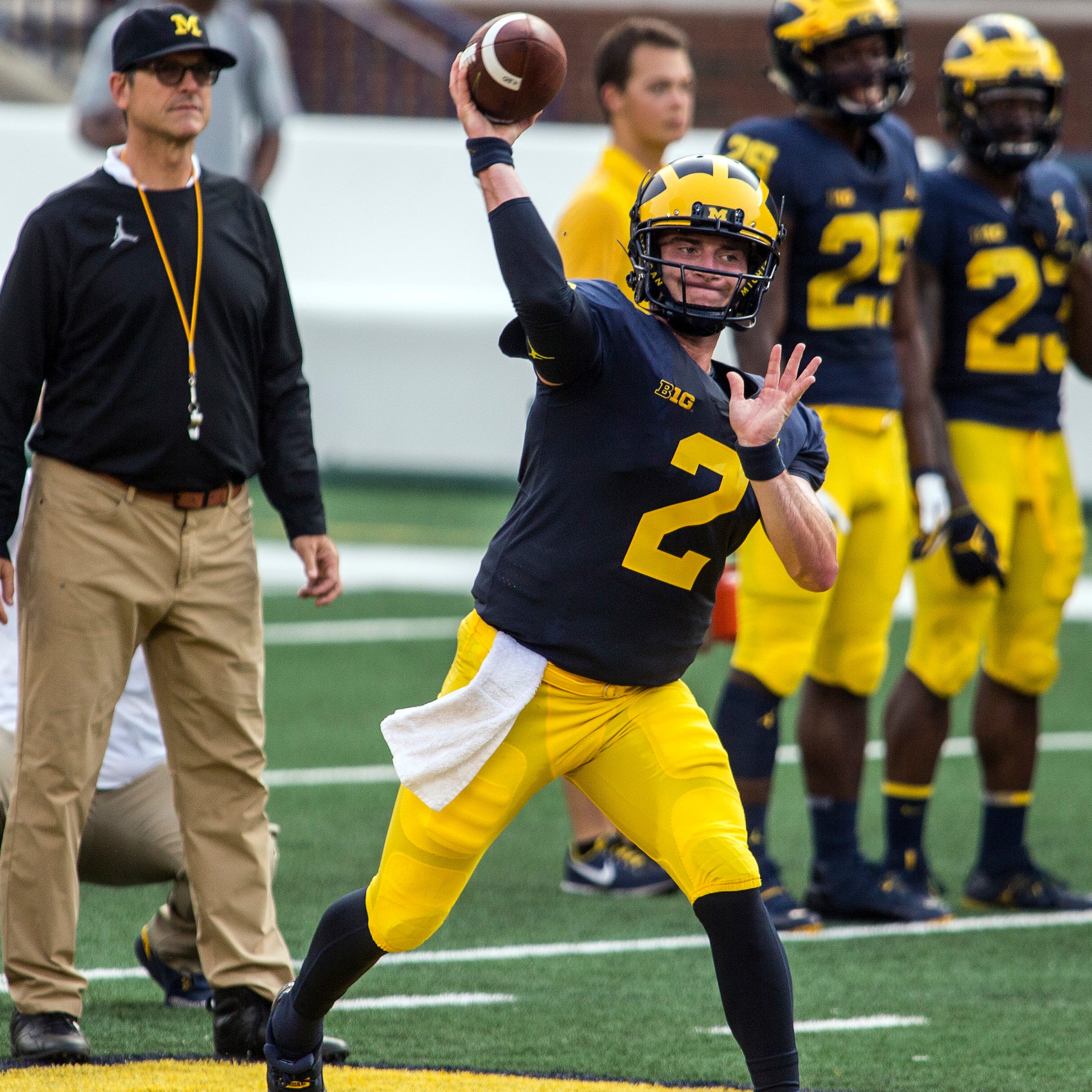 Michigan quarterback Shea Patterson throws a pass while watched by coach Jim Harbaugh during a preseason practice.