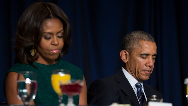 President Barack Obama and first lady Michelle Obama bow their heads in prayer during the National Prayer Breakfast in Washington, Thursday, Feb. 5, 2015,.  The annual event brings together U.S. and international leaders from different parties and religions for an hour devoted to faith. (AP Photo/Evan Vucci)  