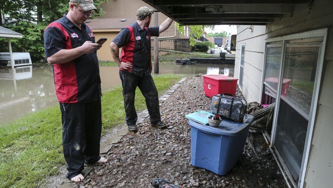 Dave Provost, left, and friend Teran Cozad try to grab items from Provost's flooded basement apartment along 75th Street in Clive Thursday June 25, 2015.