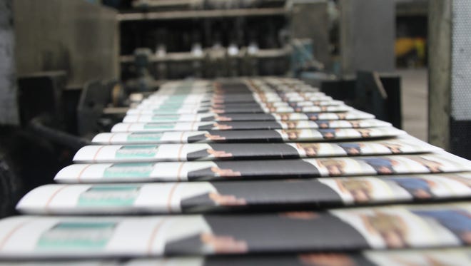 Ads roll of the press, bound for papers stacked with Black Friday sales.