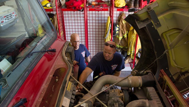 Hurricane Fire Department firefighters Eric Freiberg, left, and Chad Oliphant check the fluid in the engine of the department's brush truck as they perform maintenance on their equipment in Hurricane on Aug. 14, 2012.