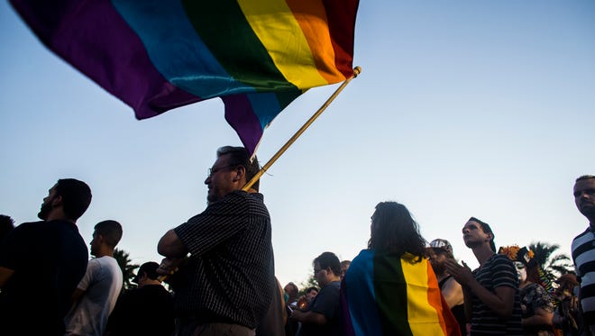 Alex Oliphant holds a rainbow flag outside Phoenix Pride during a vigil for the victims of the Orlando shooting on June 12, 2016 in Phoenix, Ariz. 