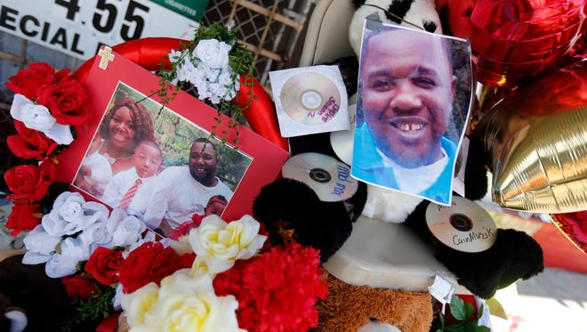 Photos of Alton Sterling are interspersed with flowers and mementos at a makeshift memorial in front of the Triple S Food Mart in Baton Rouge, La., Thursday, July 7, 2016. Sterling, 37, was shot and killed outside the convenience store by Baton Rouge police, where he was selling CDs. (AP Photo/Gerald Herbert)