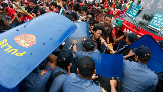Police and protesters clash during a violent protest outside the U.S. Embassy in Manila, Philippines Wednesday, Oct. 19, 2016. A Philippine police van rammed into protesters, leaving several bloodied, as an anti-U.S. rally turned violent Wednesday at the American embassy in Manila.