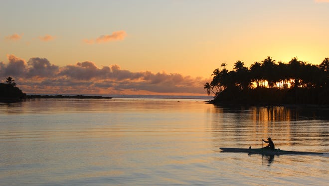 In this Oct. 30, 2015 photo, the sun rises over the lagoon in Bora Bora, as a kayaker passes by. Bora Bora offers celebrity-style seclusion and has been a vacation destination for the likes of Justin Bieber, Jennifer Aniston and Usain Bolt. It's located 160 miles from Tahiti with a balmy and relatively consistent temperature of 80 degrees Fahrenheit.