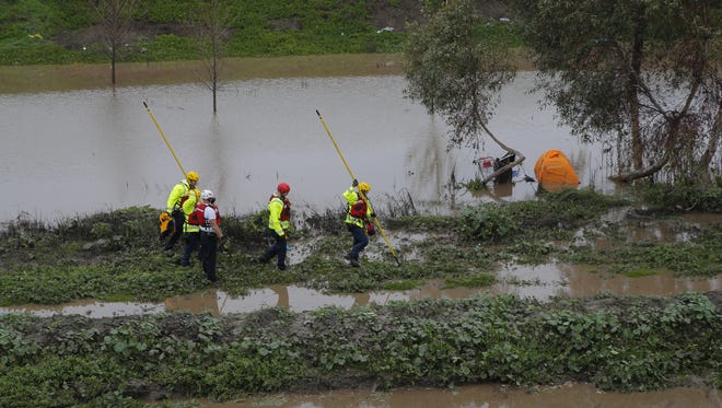 Salinas firefighters check on a flooded homeless encampment off Highway 101 south of John Street on Wednesday.