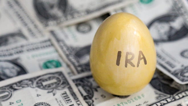 A golden egg labeled IRA is set against a background of one dollar bills.  The gold egg could represent saving for retirement in an Individual Retirement Account.