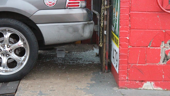Glass litters the ground in front of a door to a 3rd Street convenience store Wednesday morning. An Alexandria man was charged after a fatal shooting at the store the night before that killed an employee.