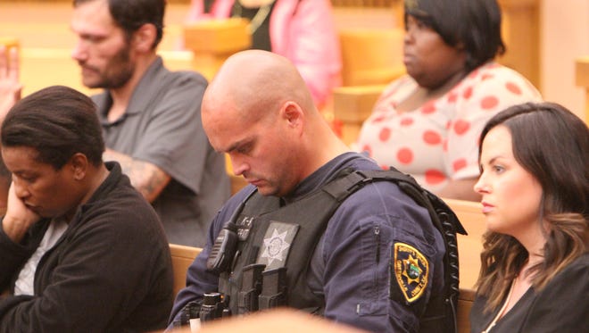 Greenville County Sheriff's Office Deputy Brandon Surratt waits in a courtroom to hear a case involving his slain police dog Hyco. In the background, in the dress with red polka dots, is Shirlandria Dixon.