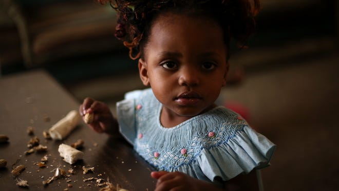 Madede Mambo, 2, eats Cassava root in the family’s living room in Tallahassee.