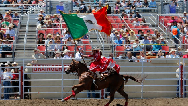 Daisey Barajas rides while waving the Mexican flag at the 107th California Rodeo Salinas on Sunday.
