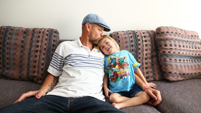 Kevin Scarbrough and his 4-year-old son Anthony snuggle at their new home in north Phoenix.