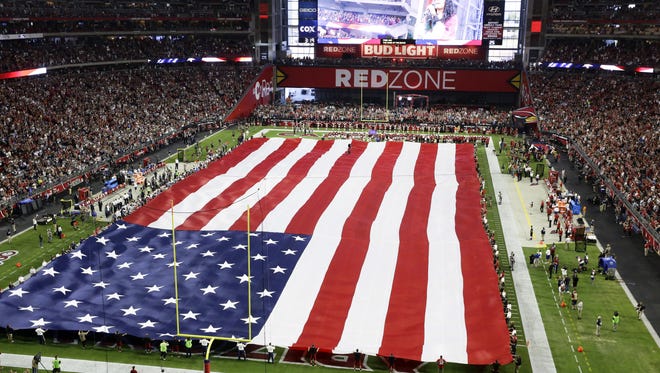 Arizona Cardinals stand with arms locked in the south end zone as the national anthem is performed during Monday Night Football on Sep. 25, 2017 in Glendale, Ariz.