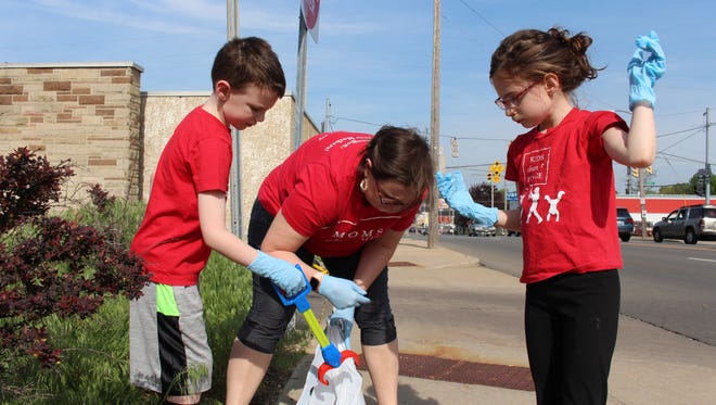 Liam Burns, Laura Burns and Sylvia Burns, from left, pick up cigarette butts near the Mansfield Municipal Building on Thursday. The family helped pick up litter downtown as part of the 22nd annual Operation Clean Sweep.