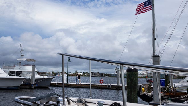 People walk along the city dock during a cloudy and windy Memorial Day weekend in Naples on Sunday, May 27, 2018. 