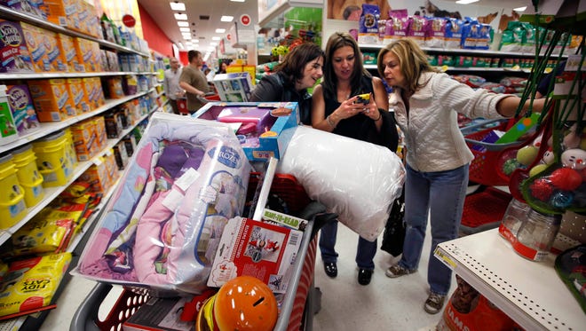 Target shoppers Kelly Foley, left, Debbie Winslow, center, and Ann Rich use a smartphone to look at a competitor's prices while shopping  shortly after midnight on Black Friday, in South Portland, Maine. The Black Friday shopping weekend may be losing its mojo. A survey of shoppers released Sunday, Nov. 30, 2014, by the National Retail Federation shows how early discounting, more online shopping and an improving economy have fewer people shopping on the weekend that kicks off the holiday shopping season. (AP Photo/Robert F. Bukaty, File)