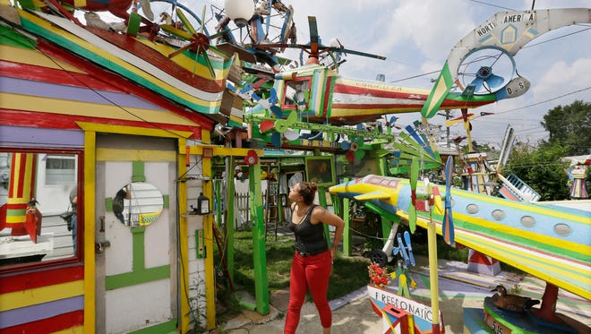 In a July 29, 2015 photo, Alyssa Kelley looks over Hamtramck's Disneyland in Hamtramck, Mich. A retired autoworker spent two decades building his backyard folk art display of brightly painted ceiling fans, rocking horses and plastic Santas that he called “Hamtramck’s Disneyland.” But since Dmytro Szylak’s death this year at age 92, the lights are dimmed and sounds quieted around the whimsical array behind the two homes he owned in the small city surrounded by Detroit.