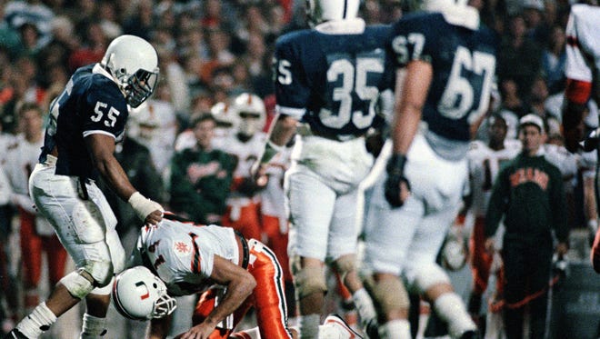 Penn State's tackle Tim Johnson (55) picks Miami quarterback Vinny Testaverde (14) up off the turf after sacking him in the second half of Friday night's Fiesta Bowl in Tempe, Ariz., Jan. 2, 1987.  Penn State won the game, 14-10.