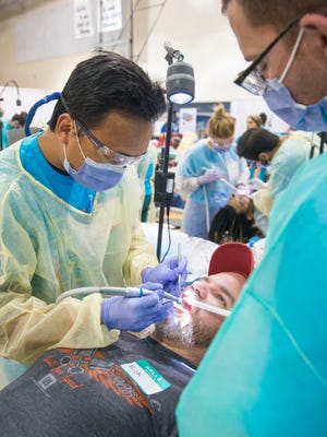 Duy Nguyen, of Palatka, left, and Anthony Farmer, of Gainesville,  treat Rick Seal during the Florida Dental Association's Mission of Mercy dental clinic at Woodham Middle School in Pensacola on Friday, March 24, 2017.
