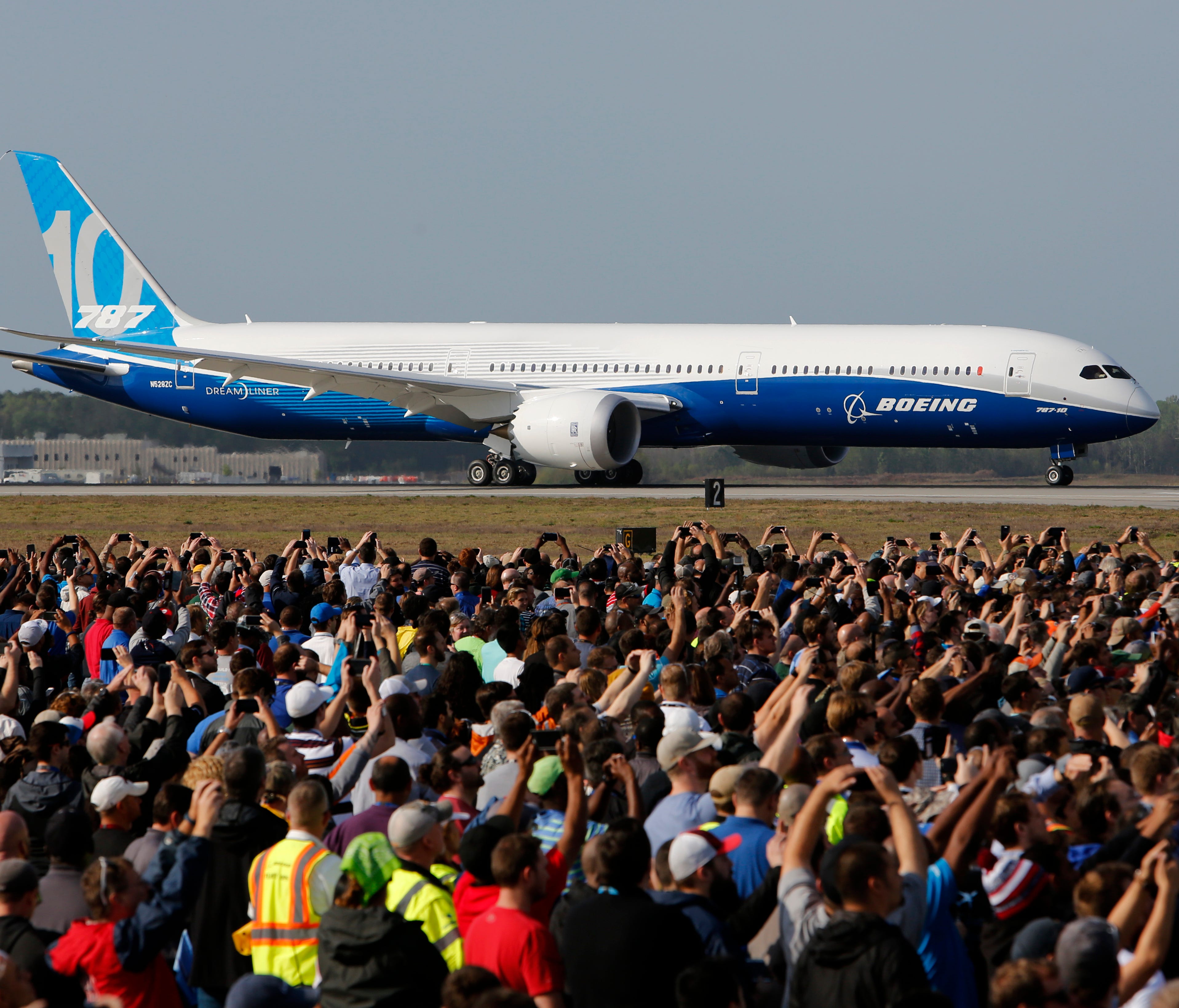 Boeing employees raise up their camera phones to record the first test flight of the new Boeing 787-10 Dreamliner as it taxis down the runway during a ceremony at Charleston International Airport in North Charleston, S.C., Friday, March 31, 2017.