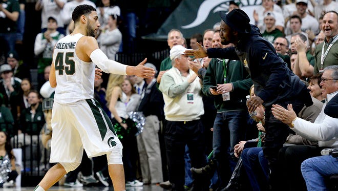 Spartans guard Denzel Valentine (45) slaps five with former Spartan football player Tony Lippett after Indiana calls timeout  in the second half of MSU's 88-69 win Sunday, Feb. 14, 2016 in the Breslin Center in East Lansing. Lippett now plays for the Miami Dolphins.