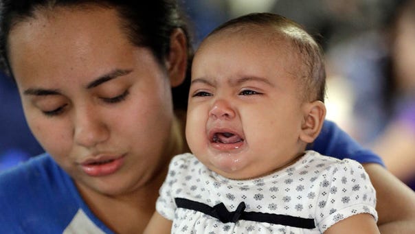 An immigrant woman from Honduras carries her crying