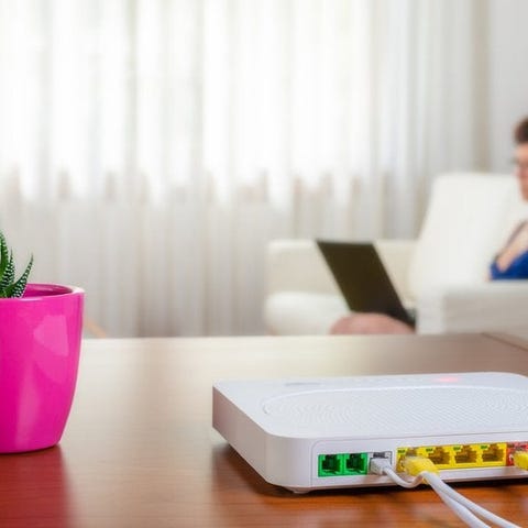 Internet router in foreground with woman using her