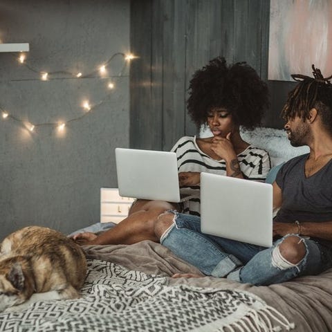 A young couple sitting on their bed with their dog