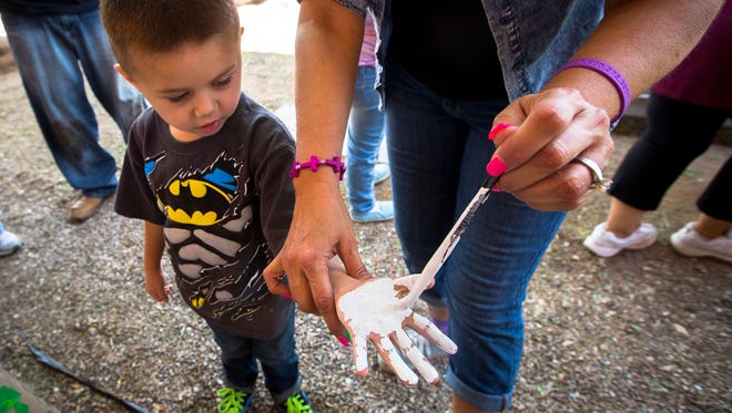 4-year-old Dominic Coyle has his hand painted white by Head Start Educational Assistant Dorean Padilla before placing it on a brick during the planting of a community garden at Booker T. Washington Elementary School, April 23, 2016. At least 40 children, school staff, family and friends worked from 9am to noon planting the garden as part of a community building program spearheaded by Azadeh Osanloo, the Stan Fulton Endowed Chair for the Improvement of Border and Rural Schools.