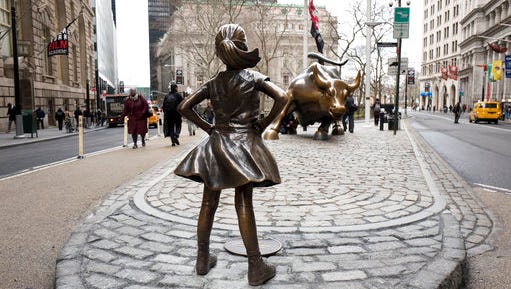 FILE In this March 8, 2017 file photo,  the "Fearless Girl" statue faces Wall Street's charging bull statue in New York.  The sculptor of Wall Street’s “Charging Bull” says New York City is violating his legal rights by forcing his bronze beast to face off against the “Fearless Girl.” Artist Arturo Di Modica said Wednesday, April 12,  that the new neighboring statue changes his bull into something negative.