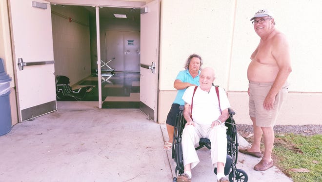 Volunteer Jenneine Lambert, left, massages the neck and shoulders of Robert Dion, an evacuee, outside the special needs shelter at Palmetto Ridge High School in Naples as Buzz Braceland looks on.