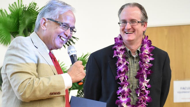 Robert Underwood, president of the Univesity of Guam, left, presents Dr. Miguel Vilar, project manager and scientific lead for the National Geographic Society's Genographic Project, with a token of appreciation at UOG on Jan. 26. Vilar's lecture revealed some recent findings about the biogeographic components of Chamorros, including having an origin in Eastern Indonesia, and having components of Native American ancestry. 
