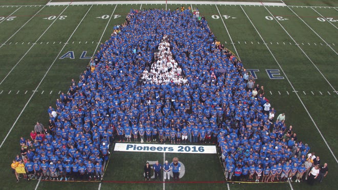 The incoming class of Alfred State students line up for a picture on the football field.