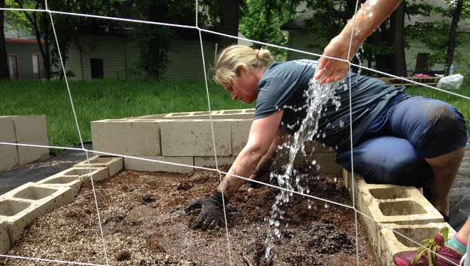Tammie Denning helps soaks compost for a square-foot garden bed for homeless families. Denning, a staffer at Inter-Lakes Community Action Partnership, helped install gardens on North Spring Avenue.
