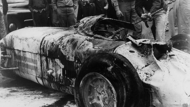 Workers at the track turn Bill Vukovich's car back onto its wheels after it flipped and burned during the 1955 Indianapolis 500.  Vukovich was killed.