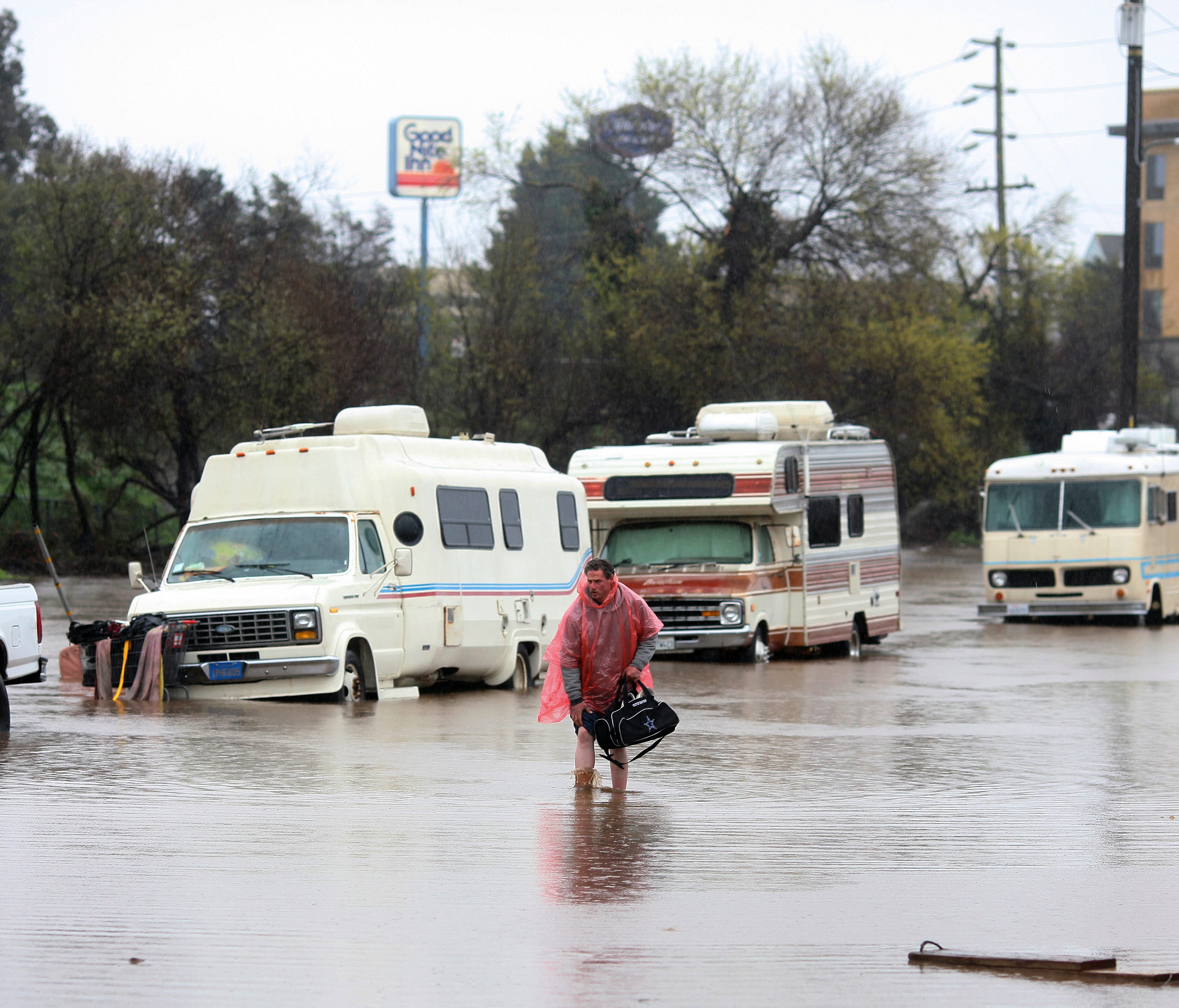 A man who lives in his RV in Salinas, Calif., walks through the flooded street on Mon., Feb. 20, 2016.