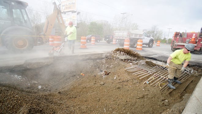 City of Mansfield employees work on fixing the hole east of the Park Avenue West bridge on Wednesday.