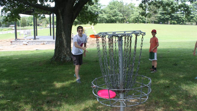 One of the communities with a disc golf course is Campbell County’s A.J. Jolly Park. Here Nick Schuler, 17, of Cold Spring, leans in as he finishes tossing an orange Frisbee in the air to a disc golf target basket in July. At right is Stephen Verst, 11, of California.
