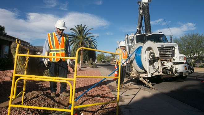 Andrew Ramirez, (left) a utility worker, and Robert Castro, an equipment operator, both with EPCOR Utilities, working in Sun City on Feb. 6, 2015.  EPCOR consolidate its five wastewater districts last year and proposes to consolidate its 11 water districts now.