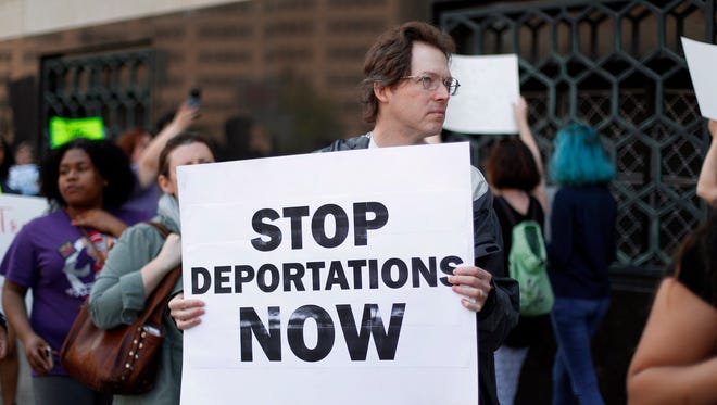 In this May 16, 2017 file photo, Don Bisdorf, of Ann Arbor, Mich., carries a sign to stop deportations at a rally outside a federal courthouse in Detroit. For years, immigrants have checked in regularly with federal deportation agents to show they've been following the country's laws even though they have been ordered to leave. Now, in cases spanning from Michigan to California, many of those who have exhausted their legal options are being told their time here is up.