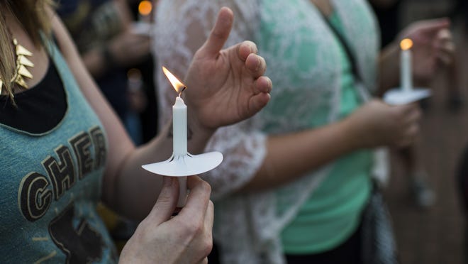 People hold candles during a candlelight vigil at Parc Sans Souci in Lafayette on July 25.