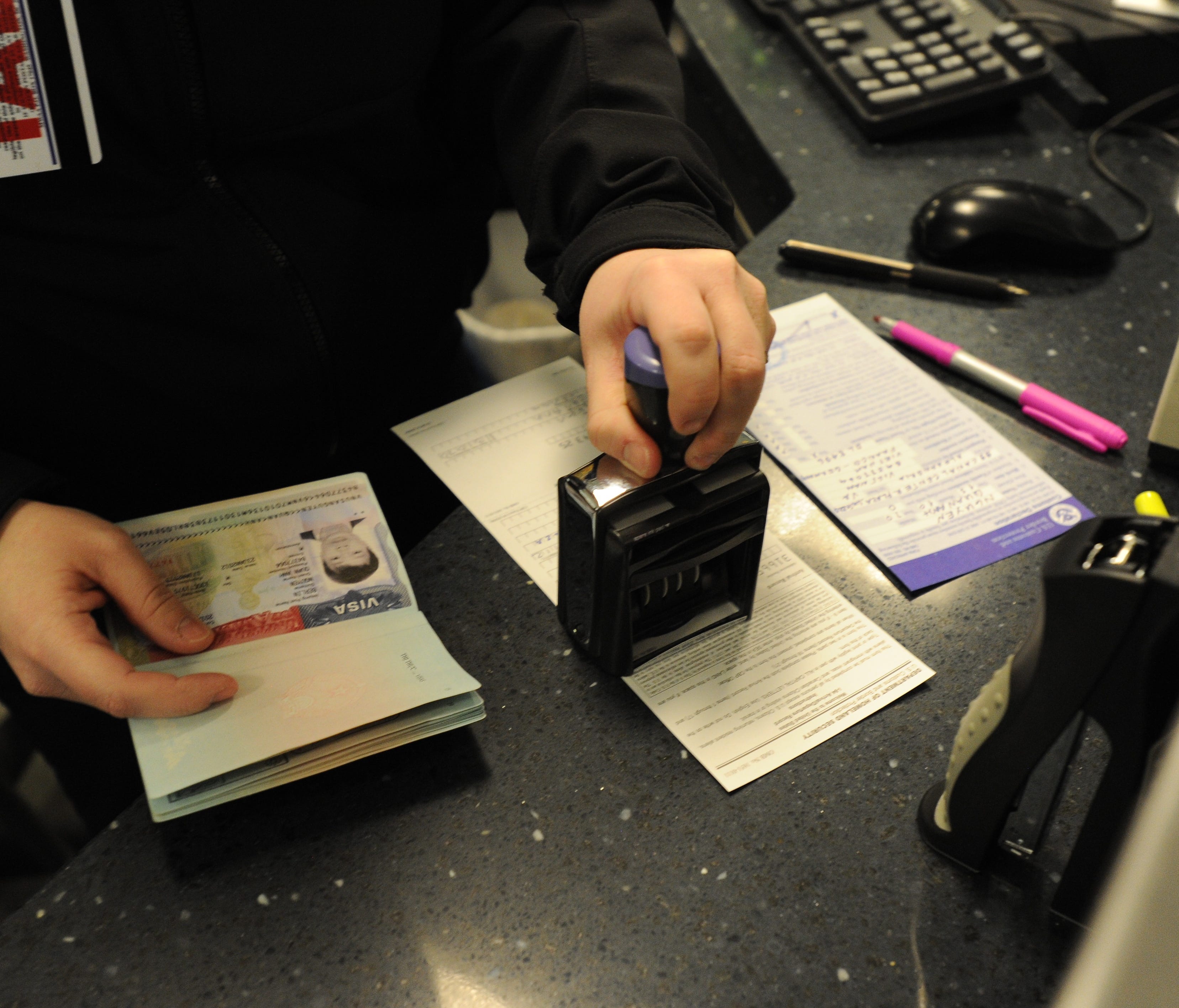 Customs agent Rebecca O'Neill stamps a visa of a non-U.S. citizen traveler at the primary inspection area at Dulles International Airport.
