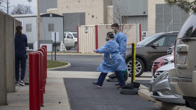 Employees from the Ohio State Martha Morehouse Outpatient Care Center perform coronavirus testing on a patient in their car on Monday, March 16, 2020.