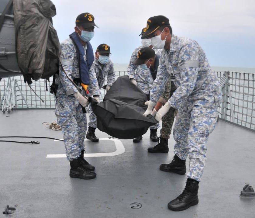 A handout photo made available by the Royal Malaysian Navy shows navy personnel with a body bag containing the remains of one of the missing sailors from the US guided-missile destroyer USS John S. McCain off the coast of Malaysia,  Aug. 22, 2017.