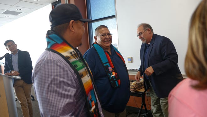 Byron Tsabetsaye, left, director of the Native American Center at San Juan College, announces the names of the 2018 PNM scholarship graduates Tuesday during a graduation ceremony at the San Juan College School of Energy in Farmington as Michael Benally, second to left, and Myron Charley receive their sash and a certificate.