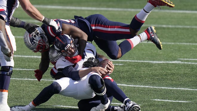 New England's Adrian Phillips, left, and Terrence Brooks combine to take down Denver running back Diontae Spencer in the first half of Sunday's game at Gillette Stadium.