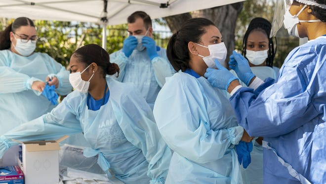 A medical team prepares to test people for COVID-19 in March, when the disease first began to claim victims, at a drive-thru center in a parking lot of FoundCare outside West Palm Beach.