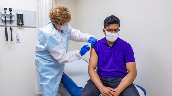 A health care professional gives a patient a flu vaccine this year at a CVS "MinuteClinic." CVS is hiring 10,000 more health care professionals this quarter to prepare for eventual distribution, which is expected to occur sometime next year, of a COVID-19 vaccine.