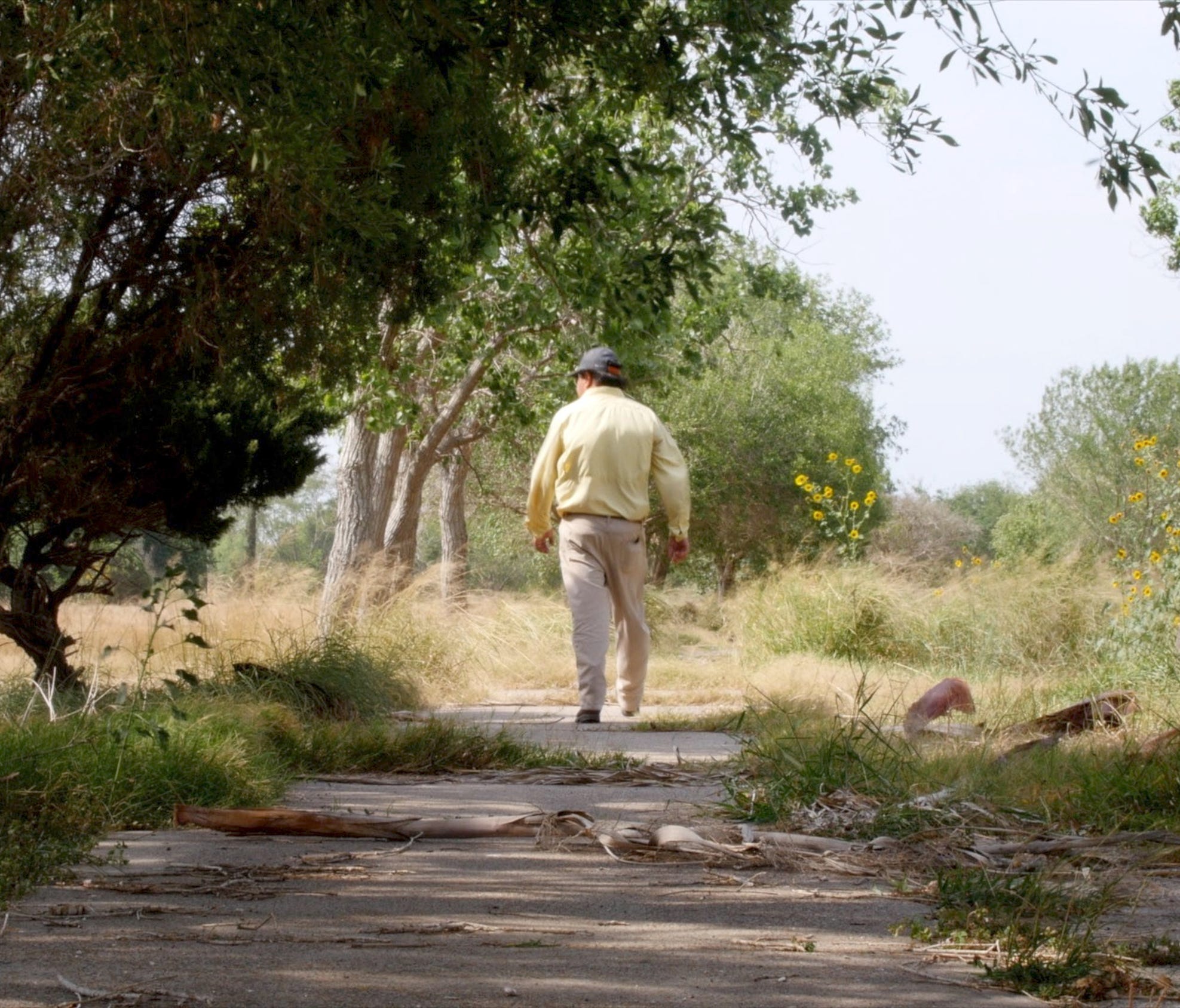 Bob Lucio, former owner of the Fort Brown Memorial Golf Course, walks along a cart path that is being covered by vegetation since the course close in 2015.